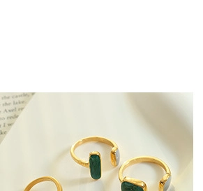 Dettaglio di anelli aperti vintage con agata verde e smalto bianco in finitura dorata