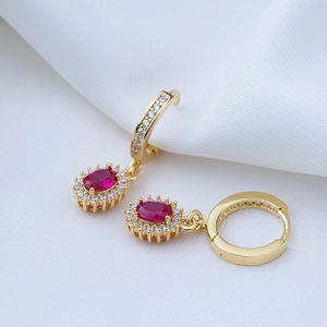 Close-up of gold-plated hoop earring with red oval gemstone and white zircon stones