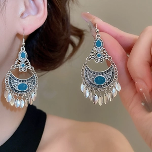 Close-up of vintage silver earrings with teal gemstones and delicate leaf tassels