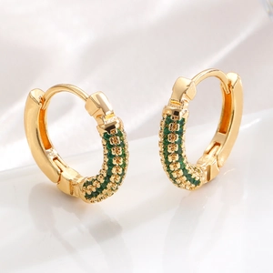 Macro detail of gold huggie earrings with pavé set green zircons on satin base
