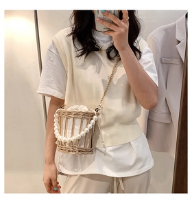 Mirror selfie showing a straw basket crossbody bag with pearl handle and chain strap