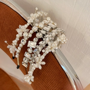 Vue détaillée de serre-têtes baroques avec perles et strass brillants sur une chaise brune.