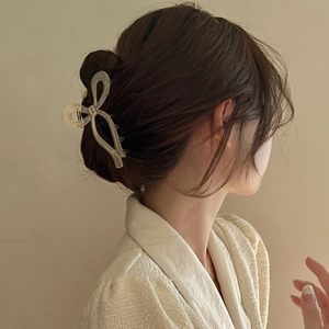 Detail of elegant ivory ribbon claw clip securing a high ponytail on model hair