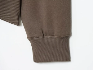 Detailed macro view of dark coffee cotton knit sleeves with high-density ribbed cuffs