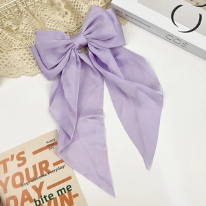 Detail of lavender satin hair bow clip with long streamers on a stylish aesthetic background