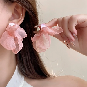 Detailed view of large pink fabric flower earrings worn to show style and size scale