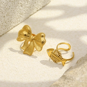 Macro shot of 18K gold plated bow and fishbone texture rings on light stone