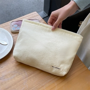 Close-up of cream corduroy makeup bag with striped texture and MAY RABBIT woven label