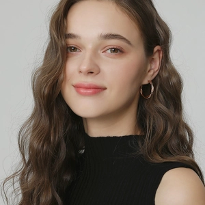 Close-up of elegant rose gold twisted hoop earrings worn by a model on a grey background