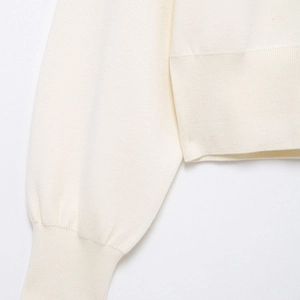 Close-up of cream knit cardigan featuring ribbed cuffs and high-density fine knit texture