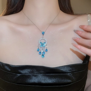 Close-up of elegant silver necklace with blue butterfly pendant and zircon tassel fringe