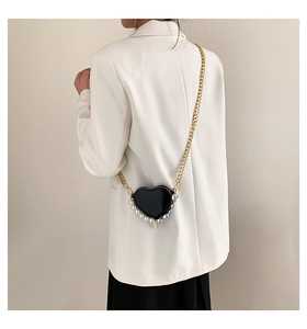 Détail du sac cœur noir en cuir crocodile avec chaîne dorée et finitions en perles