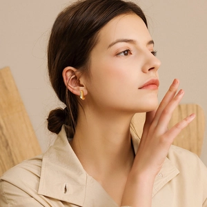 Golden C-shaped stainless steel minimalist earrings worn by model for daily wear