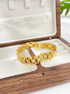 Close-up of a luxury gold-plated watchband link bracelet with sparkling diamond accents