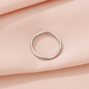 Close-up of minimalist polished silver titanium steel ring on pink fabric background