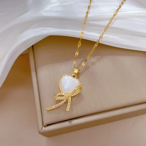 Elegant gold bow necklace with heart-shaped shell pendant and diamonds on white silk