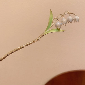 Gros plan détaillé d'une épingle à cheveux muguet avec tige dorée et pétales nacrés