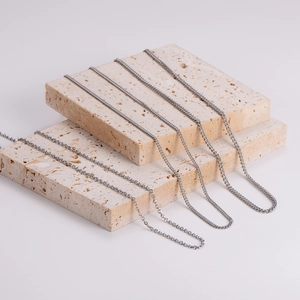 Minimalist silver triangle chain necklaces artistically displayed on beige porous stones