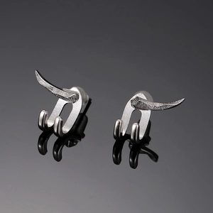 Macro shot of unique horn-shaped silver stud earrings with polished mirror reflection
