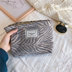 Close-up of chenille pouch with wave pattern and Time to Party label for cosmetics
