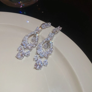 Close-up of silver zircon drop earrings with layered crystal tassels on a white plate