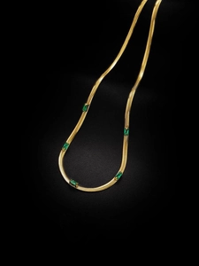 Dettaglio della catena serpente dorata con cinque pietre preziose verde smeraldo quadrate