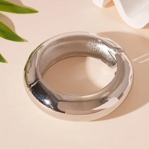 Detail view of wide silver metallic bangle with mirror finish and hinge structure