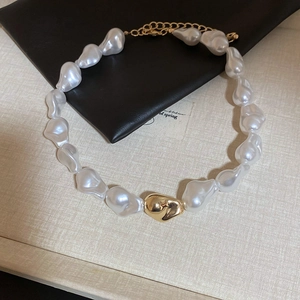 Détail d'un collier en perles baroques avec pendentif doré et chaîne réglable