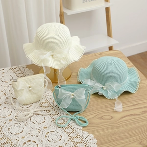 Detail of straw sun hat and matching bag with organza bows and pearl accents