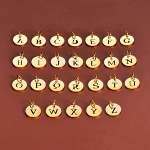 Macro view of 26 gold stainless steel 12mm round charms with hollow alphabet letters