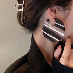 Chic oversized round acrylic earrings with black and white stripes on model
