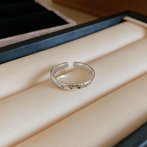 Macro shot of silver-plated oval ring with inlaid colorful zircons on velvet