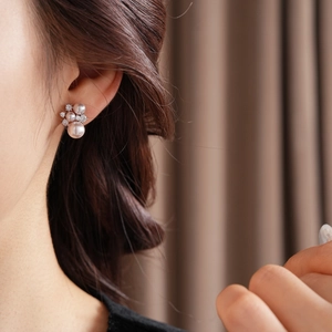 Detail of pink pearl floral earrings with cubic zirconia on model's ear in soft light
