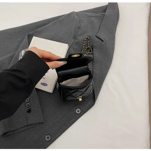 Détail du sac bandoulière en similicuir noir matelassé avec chaîne et fermoir doré chic