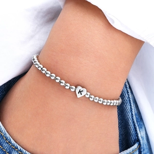 Detailed shot of a silver beaded heart bracelet with letter K charm worn by a model