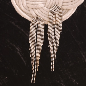 Macro detail of gold-plated tassel earrings with sparkling white cubic zirconia fringe