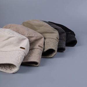 Detail of five colors of washed cotton bucket hats with retro metal emblem and stitching