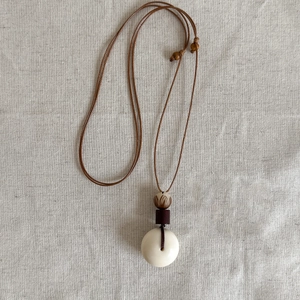 Détail du pendentif à trois niveaux en graines de Bodhi et bois sur cordon marron