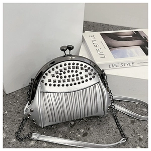 Detail of silver metallic shell bag featuring black studs and fringe chain textures