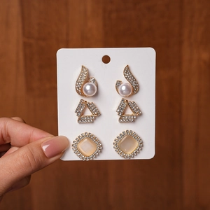 Detail of a 3-pair earring set featuring pearls, geometric triangles, and cat eye stones