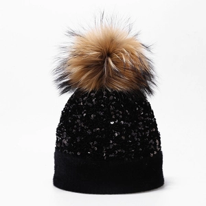 Detailed close-up of a sparkling black sequin knit beanie featuring a fluffy pom-pom top