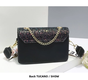 Detail view showing the back side of a black crossbody bag with wide patterned strap