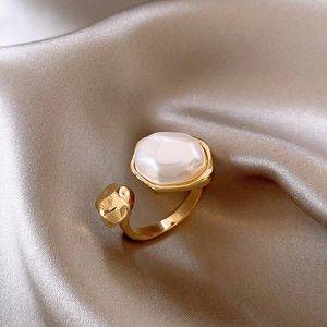 Detail of vintage irregular pearl ring on champagne satin fabric with gold plating