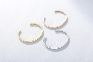 Detailed view of C-shaped open bangles in gold, rose gold and silver finishes