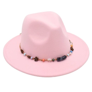 Detail of pink wool fedora hat featuring a beaded cord band and vintage flower pendant