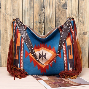 Detail of woven boho tote bag with geometric patterns, fringe tassels, and leather straps
