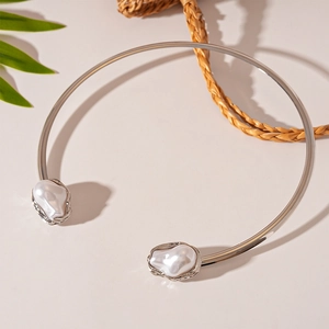 Silver choker with baroque pearls on beige background with tropical leaf and woven bag decor