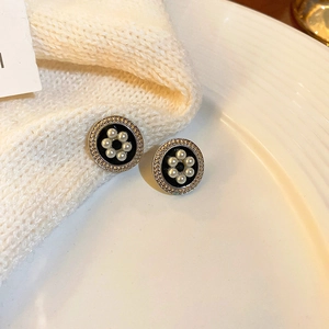 Close-up of vintage black earrings with pearls and rhinestones on soft fabric texture