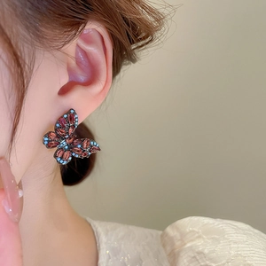 Close-up of vintage butterfly earrings with red zircon stones on a model's ear