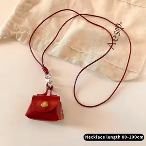 Detail view of a mini red leather bag pendant with long cord and 80-100cm length marker
